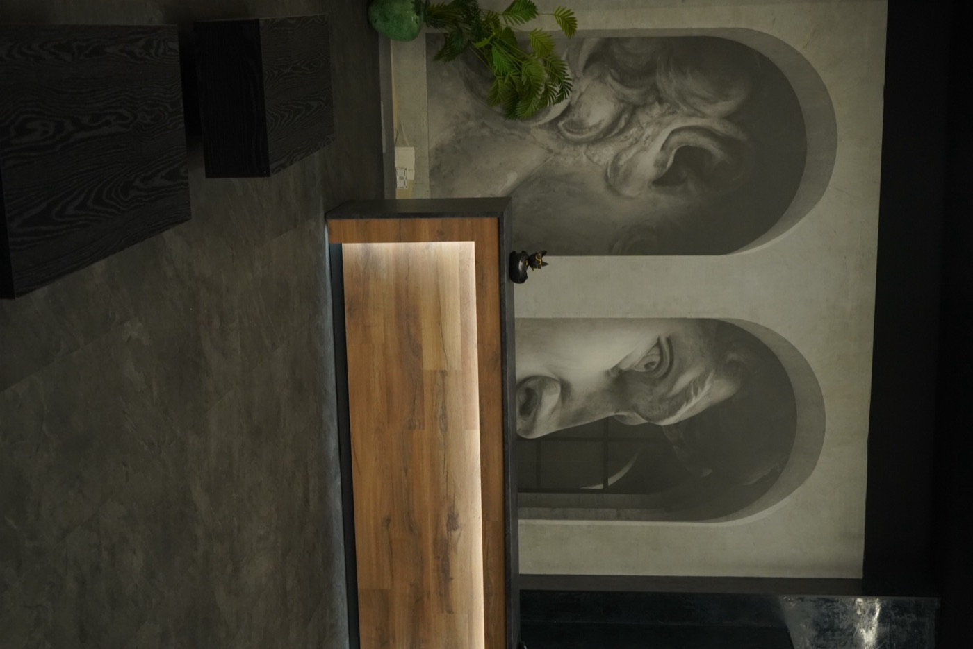 Recepción del estudio con mural de esculturas clásicas y mostrador de madera iluminado